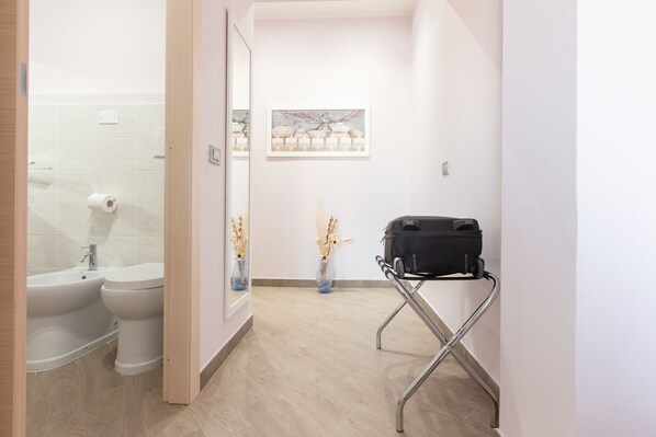 A modern bathroom with a toilet, bidet, and a small table with a suitcase. - A View on Cagliari (Cagliari)
