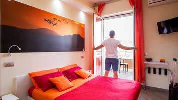Een hotelkamer met een bed, een schilderij van vogels, een televisie en uitzicht op buiten.