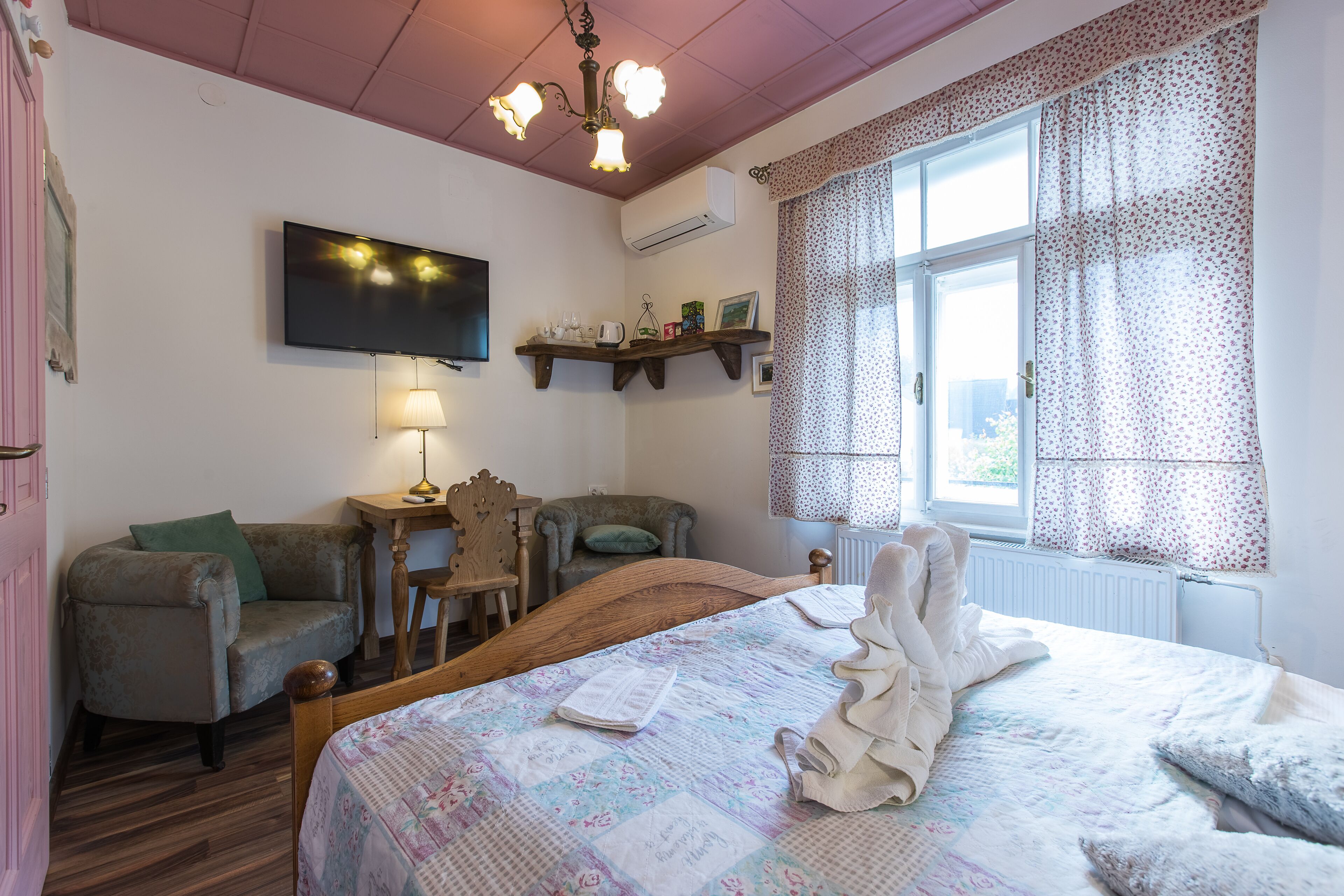 Een gezellige slaapkamer met een bed, een stoel, een klein tafeltje en een televisie.