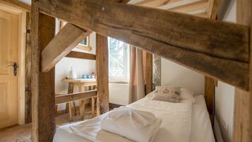 A rustic wooden room with a bed, a small table, and a window.