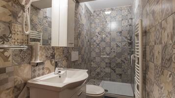 Un baño con baldosas estampadas, un lavabo, un inodoro y una zona de ducha.
