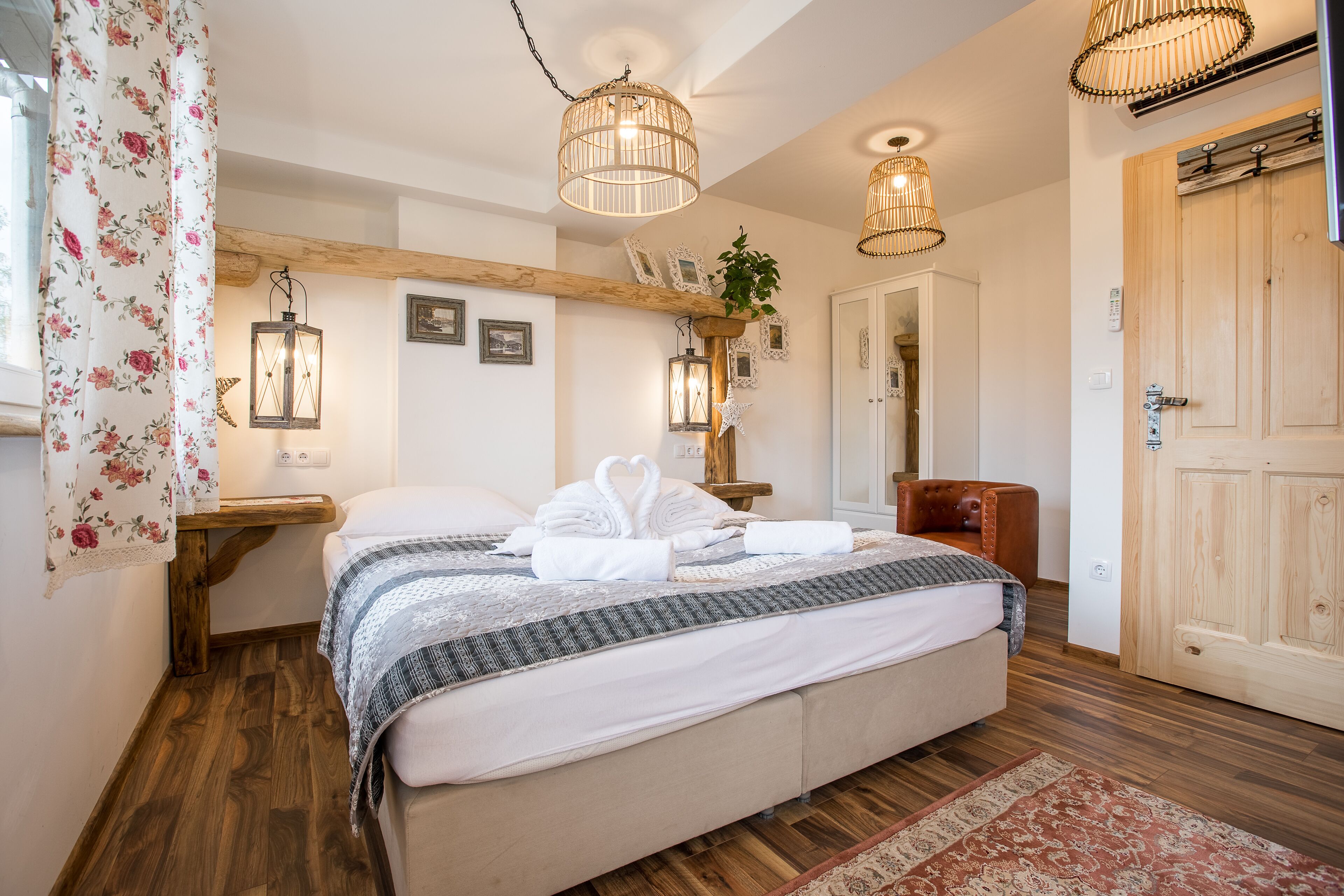 Un dormitorio con una cama, vigas de madera, una puerta de madera y dos faroles en la pared.