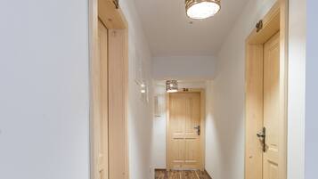 Un pasillo con suelo de madera, puertas de madera y una lámpara en el techo.