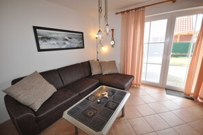 A living room with a brown leather sofa, a coffee table with a decorative top, a framed picture on the wall, and a window with curtains.