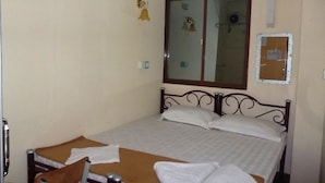 A single bed with a wooden frame, a window with a view, and a wall-mounted air conditioner. - Yangon Heart Guest House (Yangon)