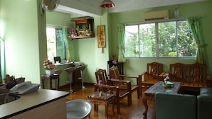 A room with a dining table, chairs, a sofa, a desk with a telephone, and a window with curtains. - Yangon Heart Guest House (Yangon)