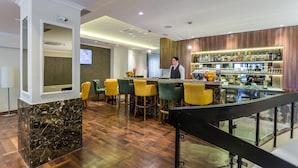A modern bar area with a marble counter, wooden flooring, and a variety of bar stools. - Hotel Royal Inn (Belgrade)