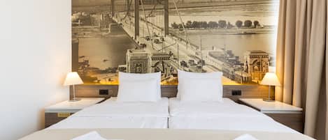 Una habitación de hotel con una cama grande, dos mesitas de noche y un mural en la pared de un puente.