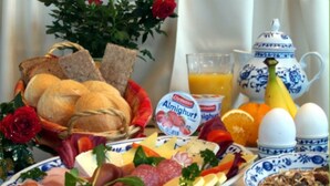 Ein Frühstückstisch mit Brot, Käse, Eiern und Obst.