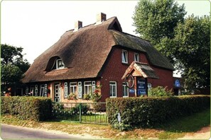 A traditional building with a thatched roof, a brick facade, and a sign indicating it is a pub.