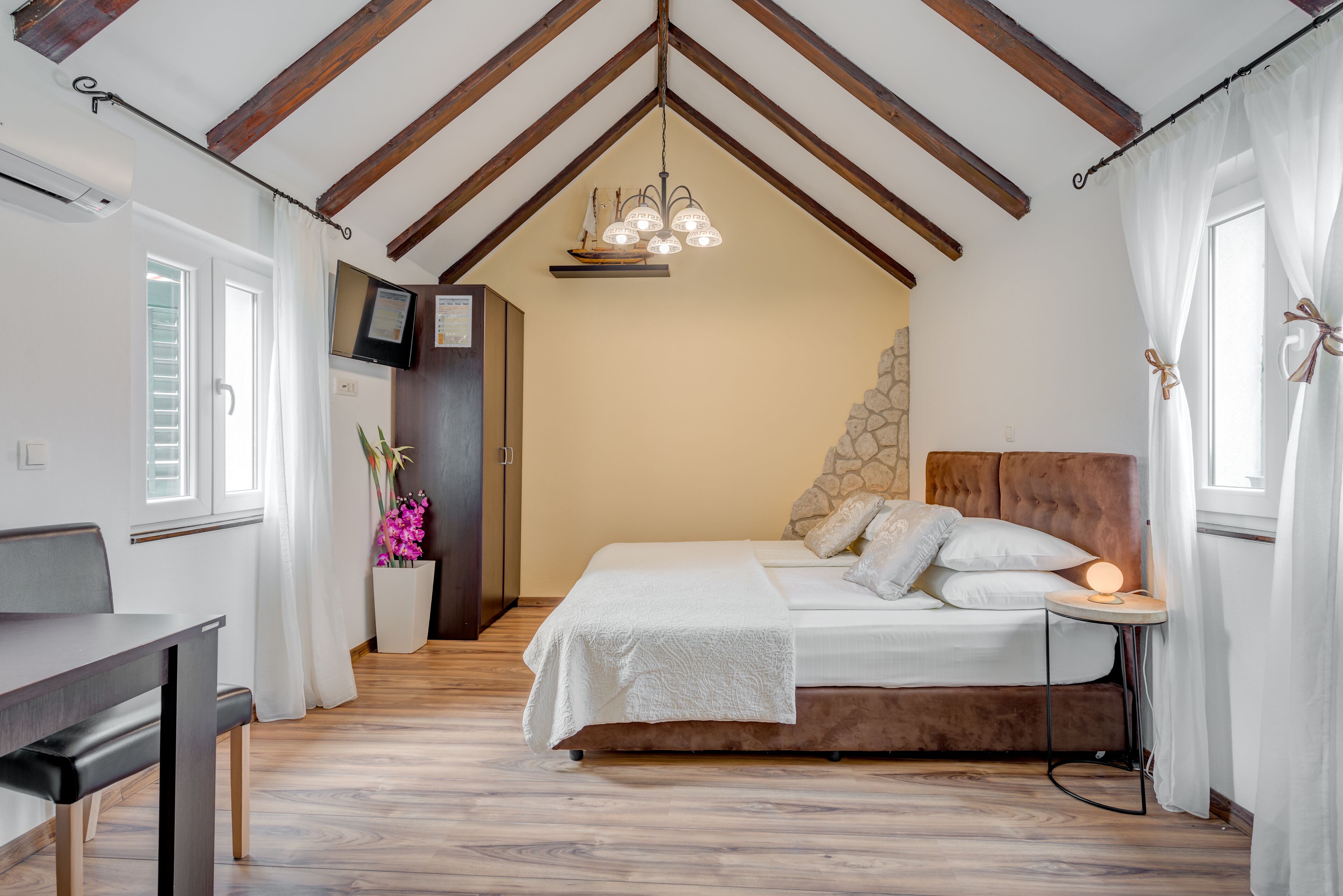 Une chambre à coucher avec un lit, une table de chevet et un téléviseur fixé au mur.