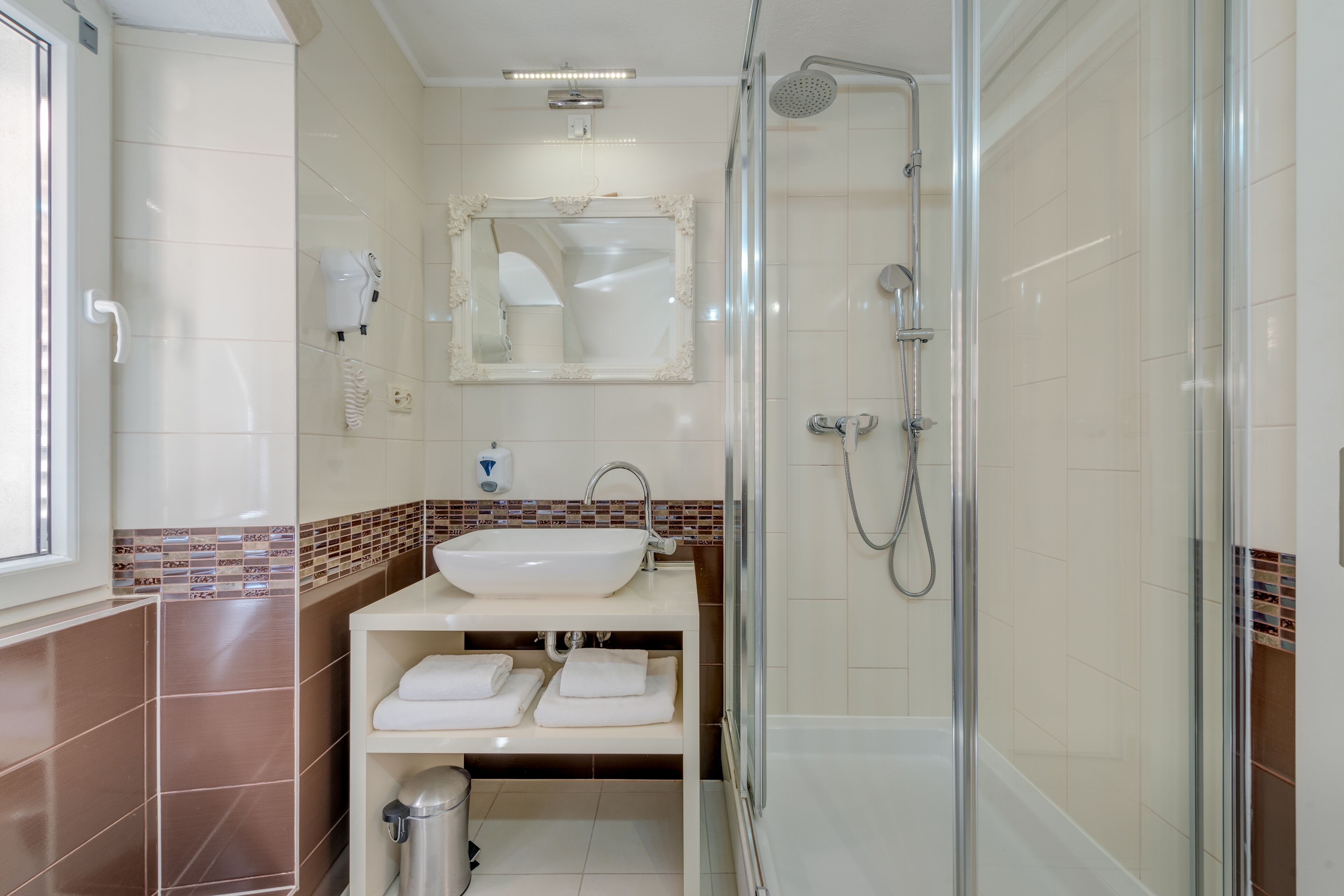 A bathroom with a glass-enclosed shower, a white sink, and a mirror above it.