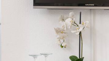 A white table with a tray holding white cups and a vase with white orchids.