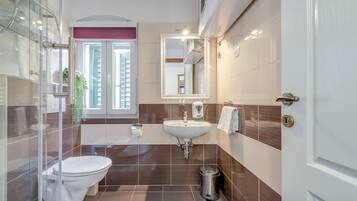 A modern bathroom with a glass shower enclosure, a white sink, and a toilet.