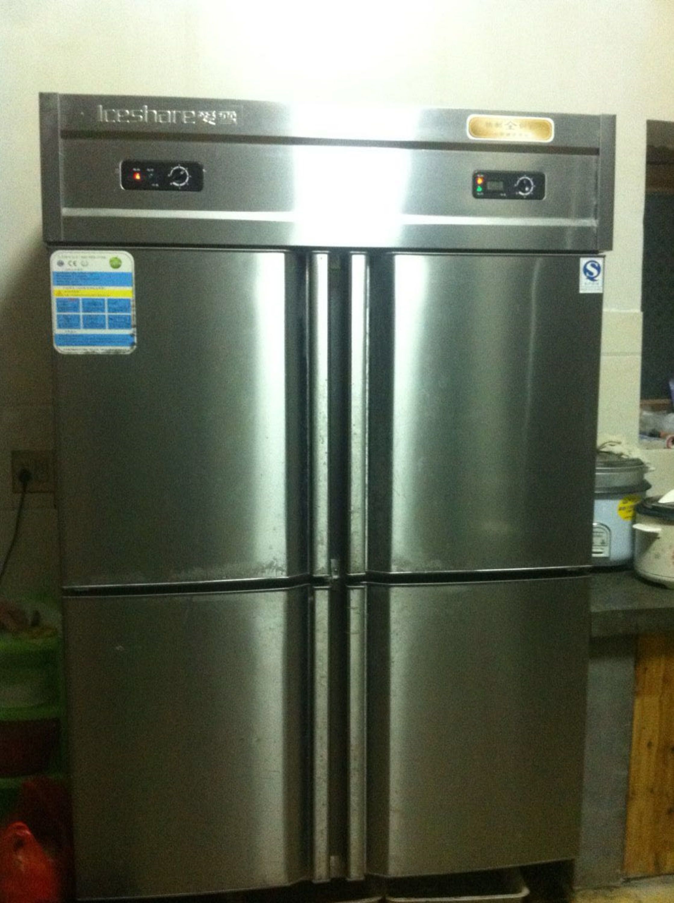 A stainless steel refrigerator with a digital display and control panel, located in a kitchen setting.
