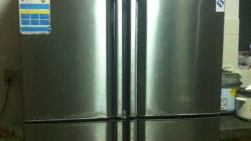 A stainless steel refrigerator with a digital display and control panel, located in a kitchen setting.