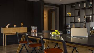 A modern dining area with a long table, six chairs, and a laptop on the table.