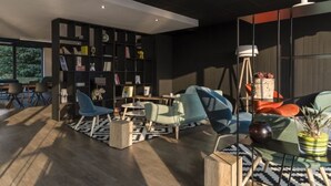 Een moderne woonkamer met een boekenkast, zithoek en een lamp.