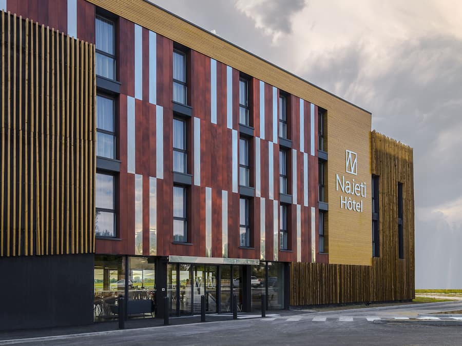 A modern hotel with a flat roof, large windows, and a prominent sign.