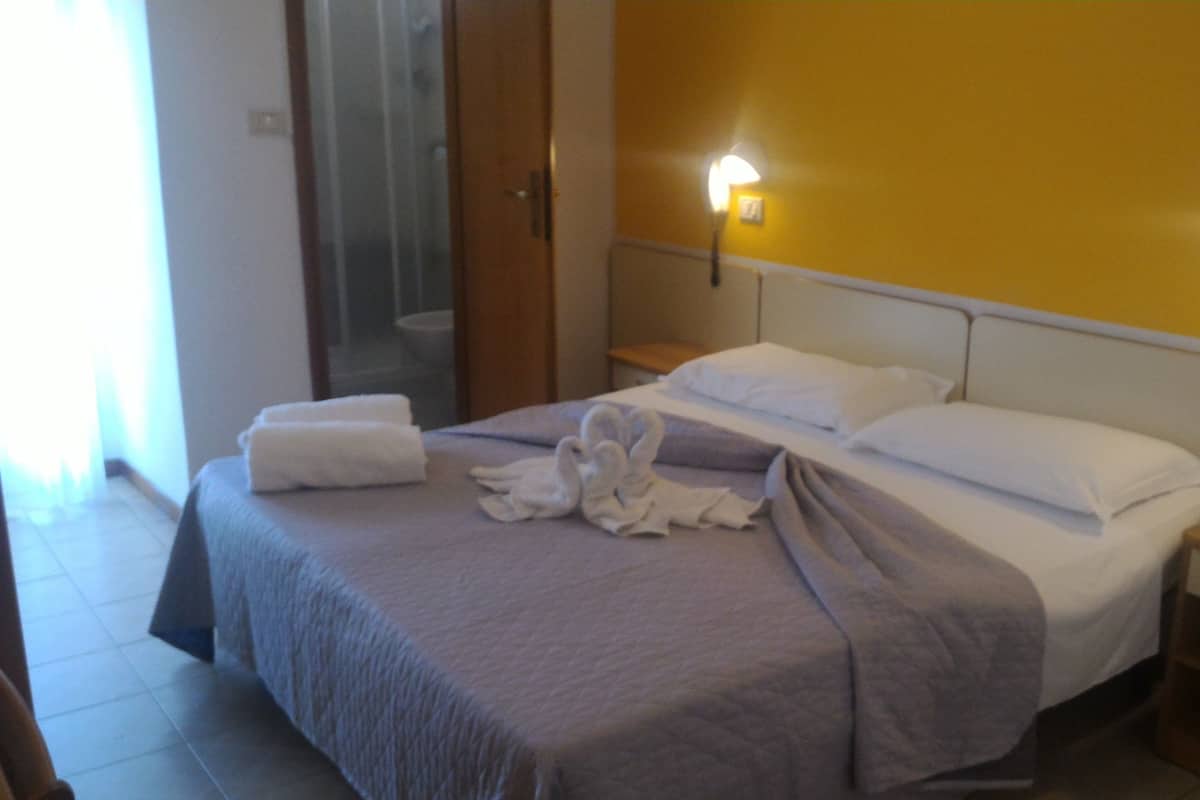 A hotel room with a bed, two bedside tables, and a mirror.