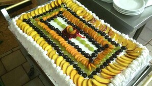 A rectangular cake with white frosting and fruit decorations.