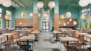 Un restaurante espacioso con techos altos, faroles de papel colgantes y diversas opciones de asientos, incluyendo mesas y sillas de mimbre.