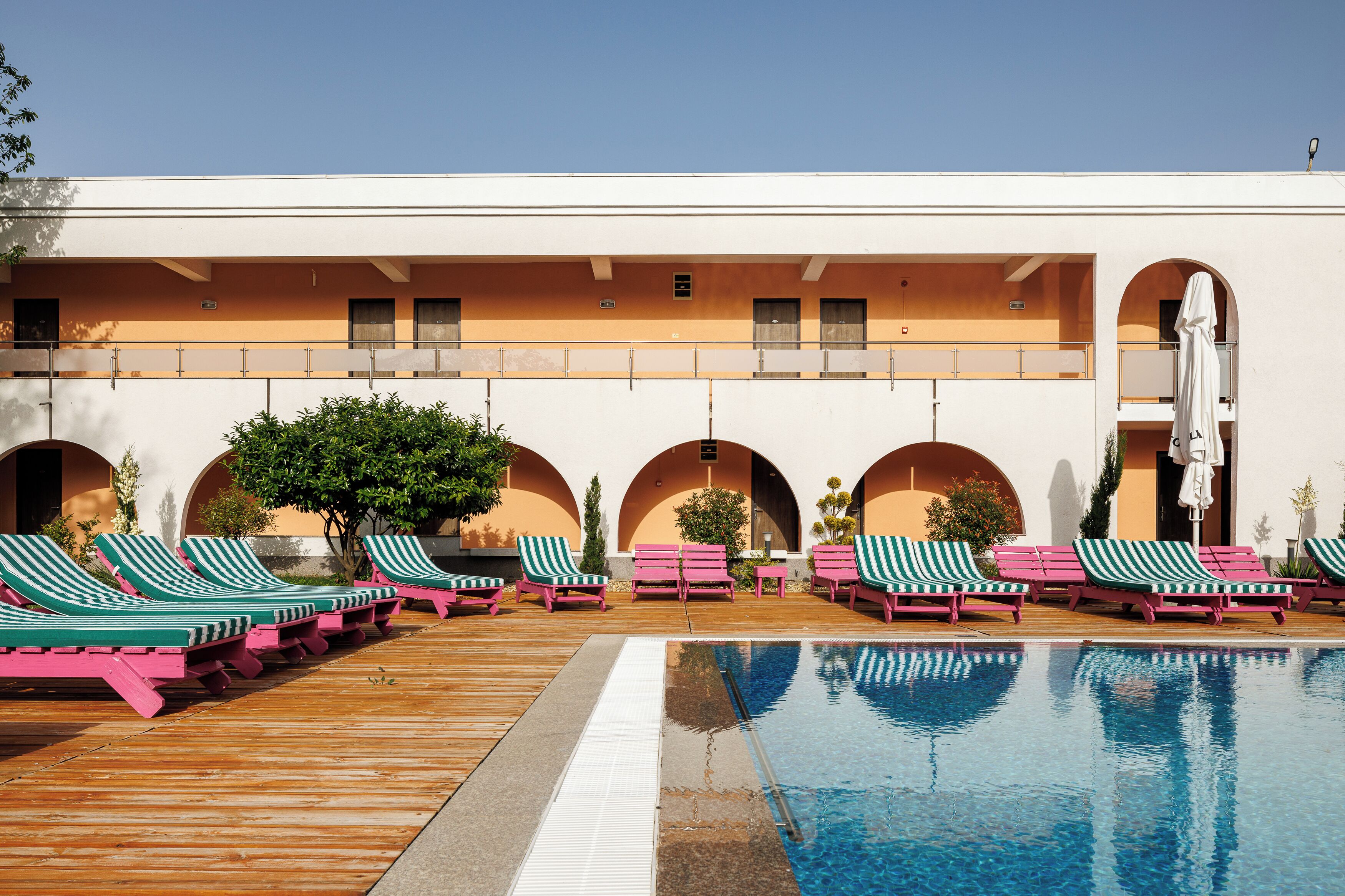 A pool area with lounge chairs and a clear blue pool.