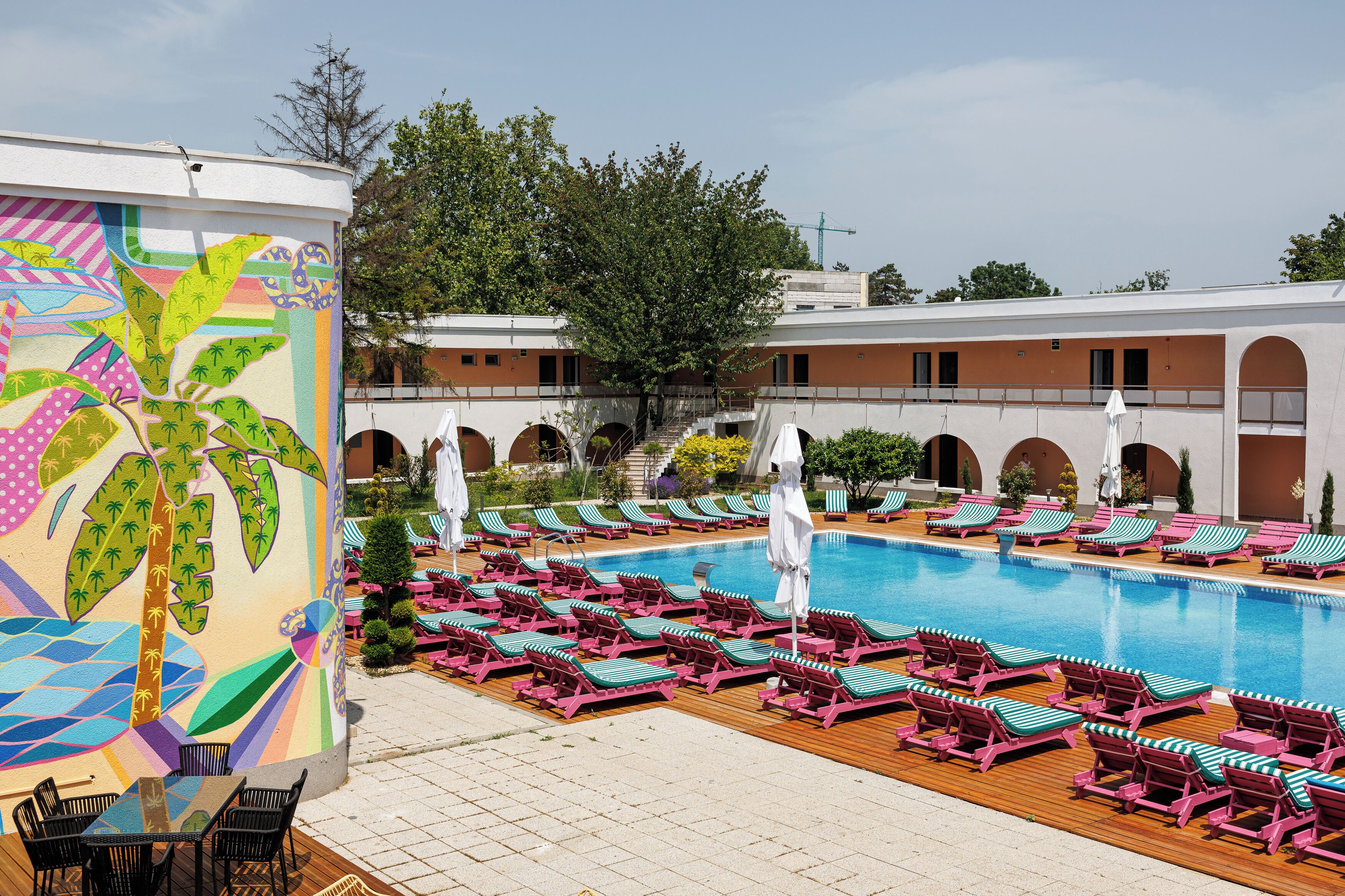 A swimming pool with sun loungers and a mural.
