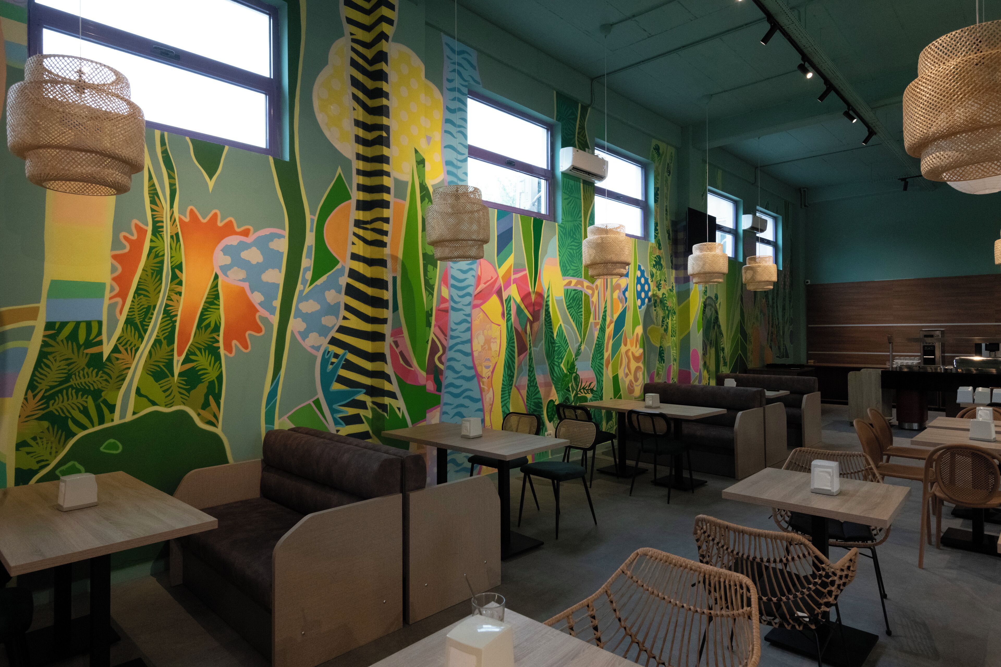 A restaurant with colorful murals, wooden tables, and wicker chairs.