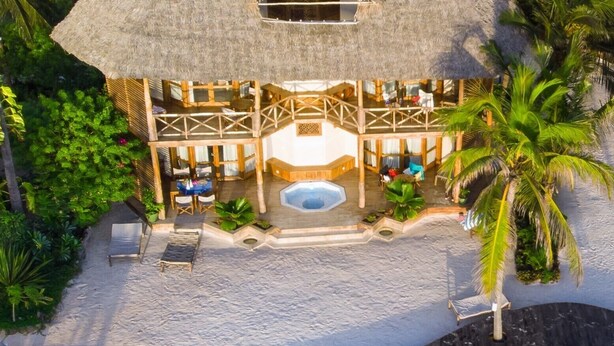 A resort with a thatched-roof structure, a swimming pool, and surrounding palm trees. - Zanziblue (Matemwe)