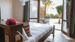 A bedroom with a bed, a desk, and a view of the outdoors. - Zanziblue (Matemwe)