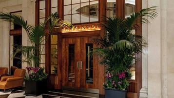 A lobby with a checkered floor, wooden doors, and potted plants.