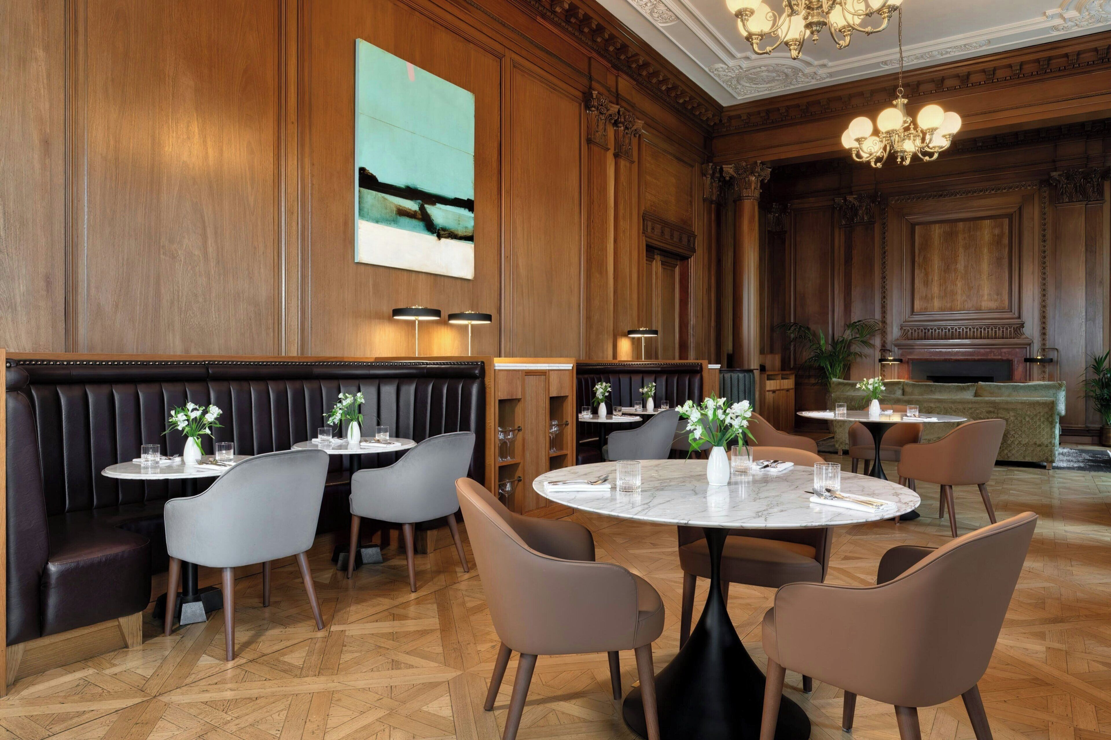 A restaurant with wooden paneling, marble tables, and leather booths.