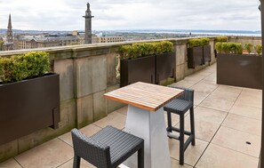 A rooftop terrace with a table and two chairs, surrounded by planters and a city view. - The Edinburgh Grand, a Luxury Collection Hotel, Edinburgh (Edinburgh)