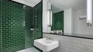 A modern bathroom with green-tiled walls, a white sink, and a large mirror.