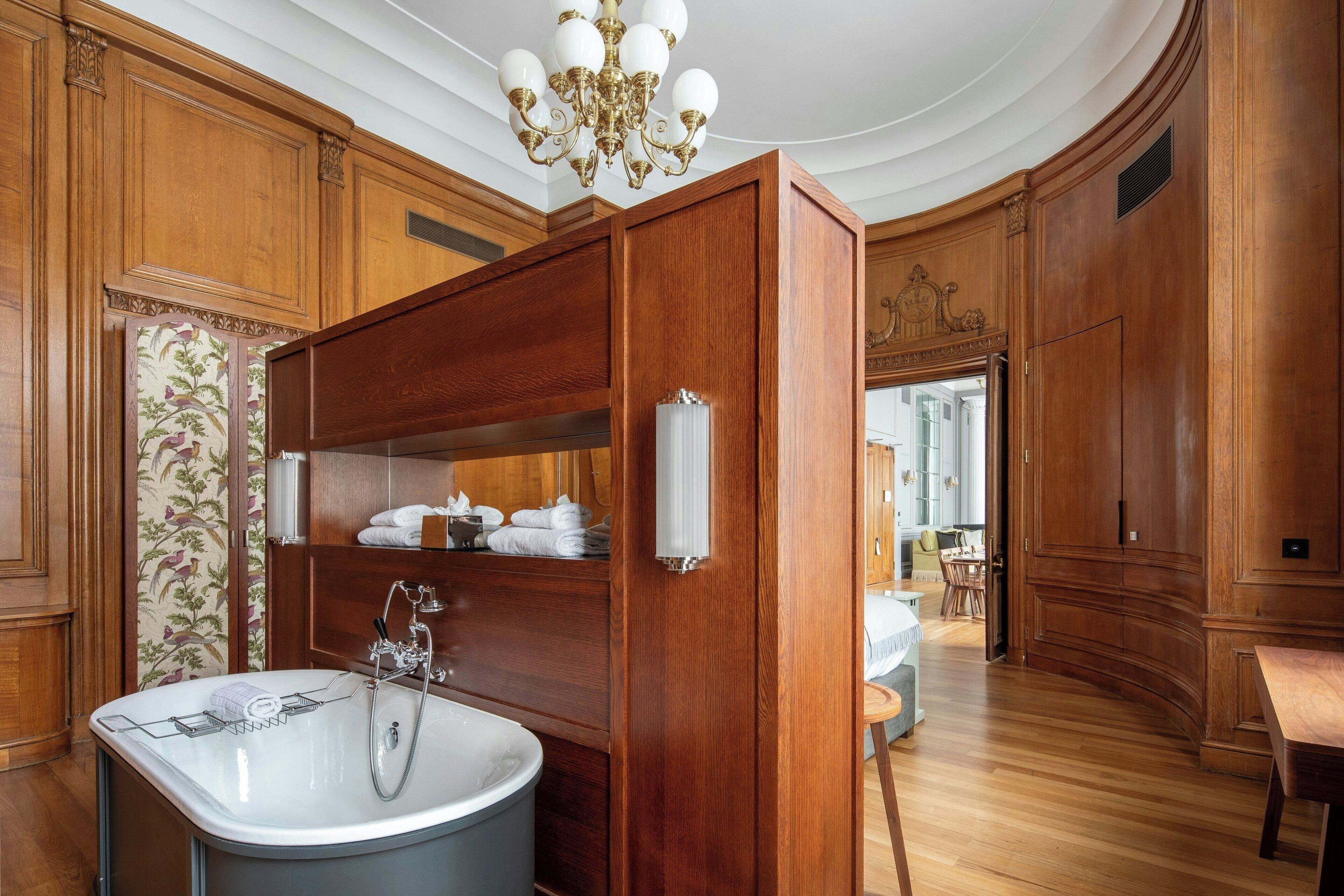 Une salle de bain luxueuse avec une baignoire sur pieds, des meubles en bois et un lustre.