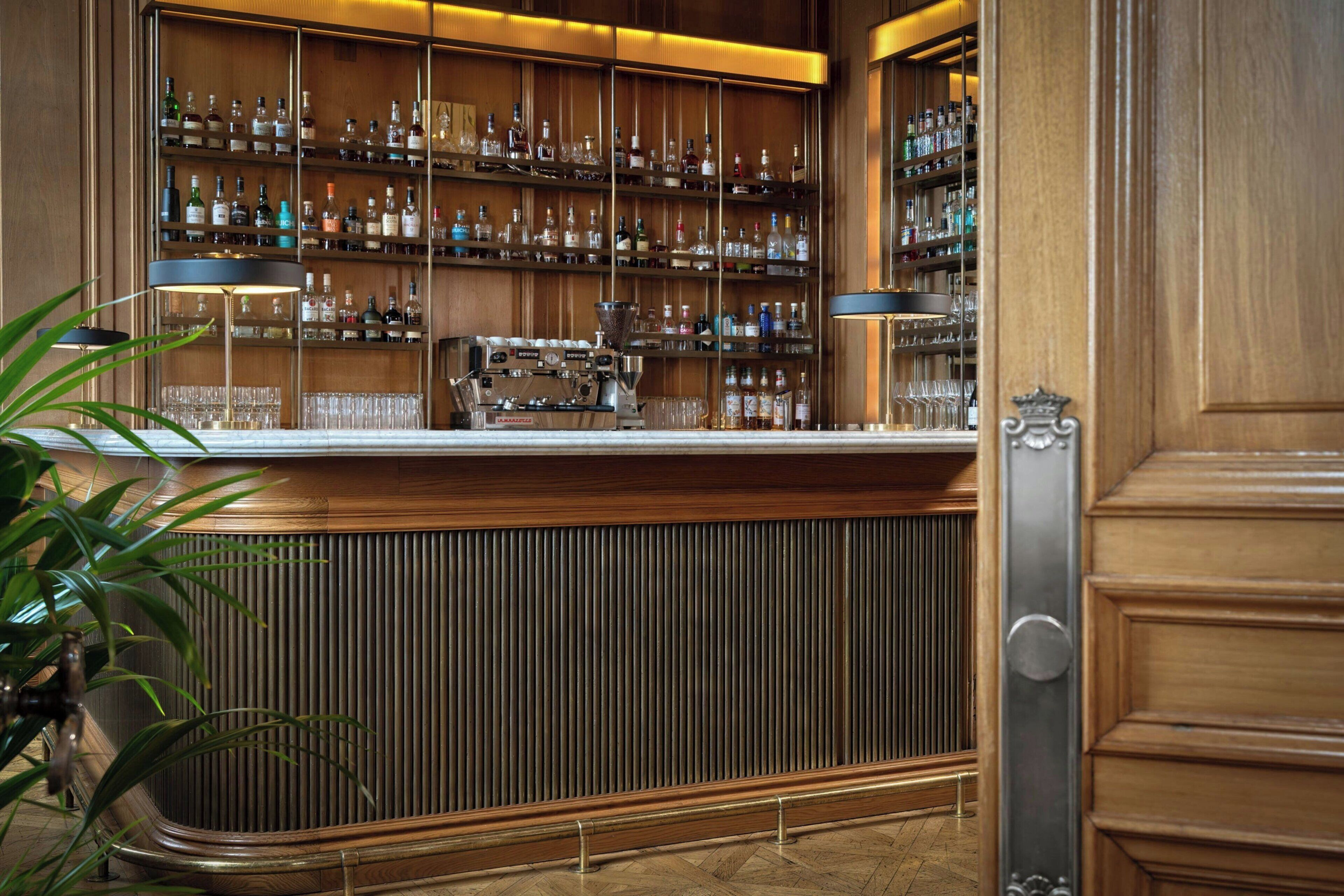 A bar area with shelves of bottles, a coffee machine, and a plant.