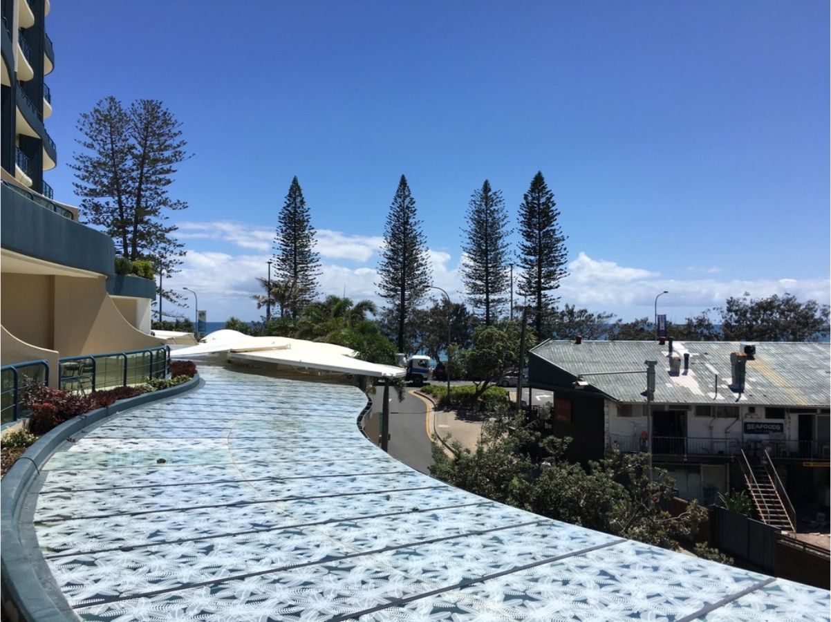 A curved pathway with a patterned surface, surrounded by buildings and trees.