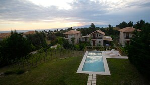 A residential area with a swimming pool, surrounded by houses with tiled roofs and a grassy lawn. - Fruit Garden Villa (Kassandra)