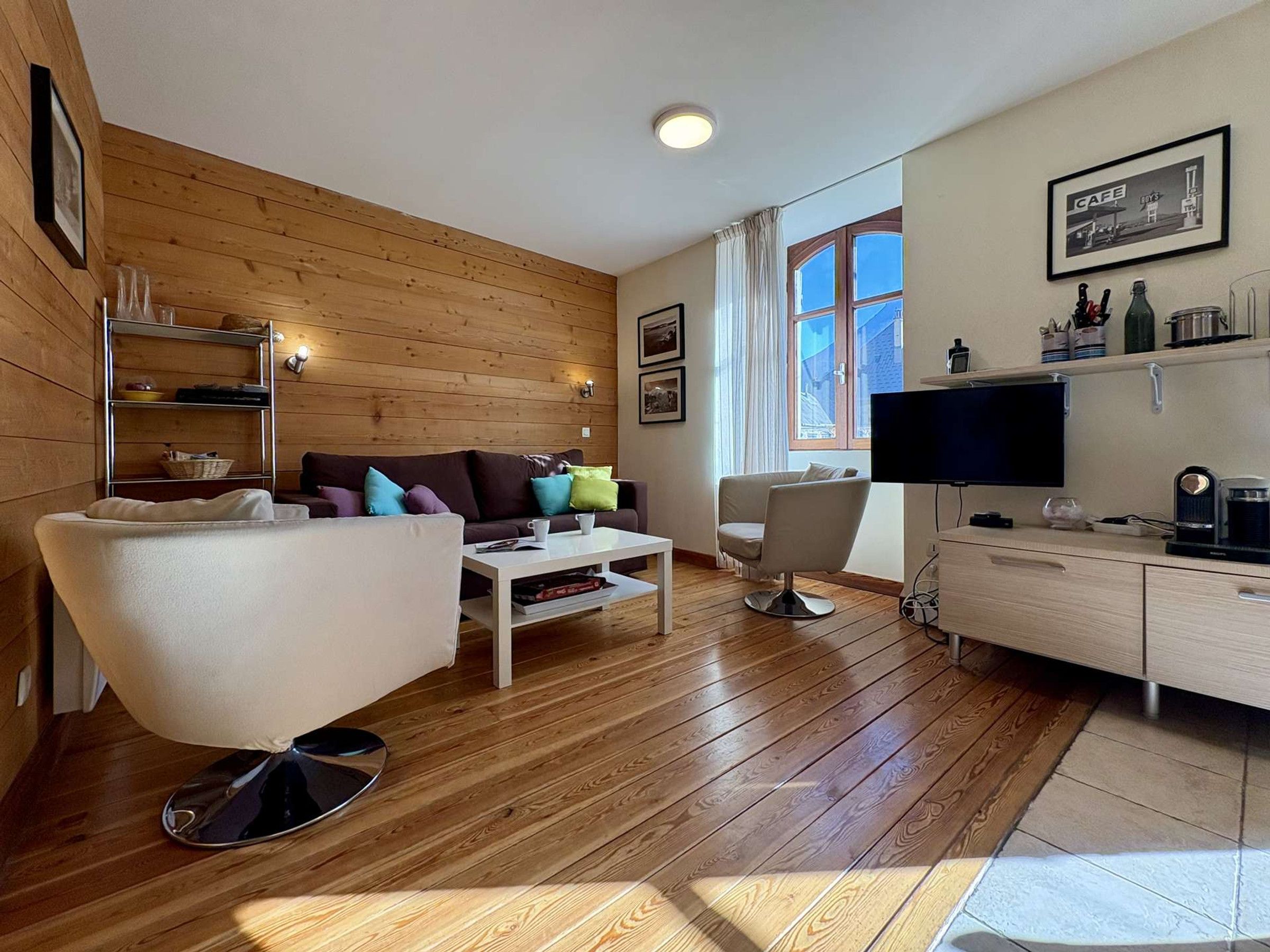 A modern living room with a sofa, armchair, coffee table, and a television.