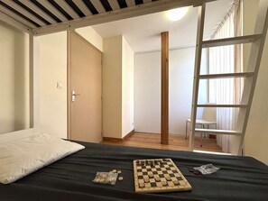 A bedroom with a bed, a wooden ladder, and a chessboard. - Renovated 3-room apartment, near station and lifts (Briançon)