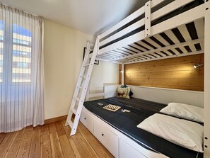 A bunk bed with a ladder, a wooden headboard, and a chessboard on the mattress.