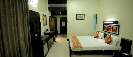 A hotel room with a bed, a desk, a television, and a wardrobe.