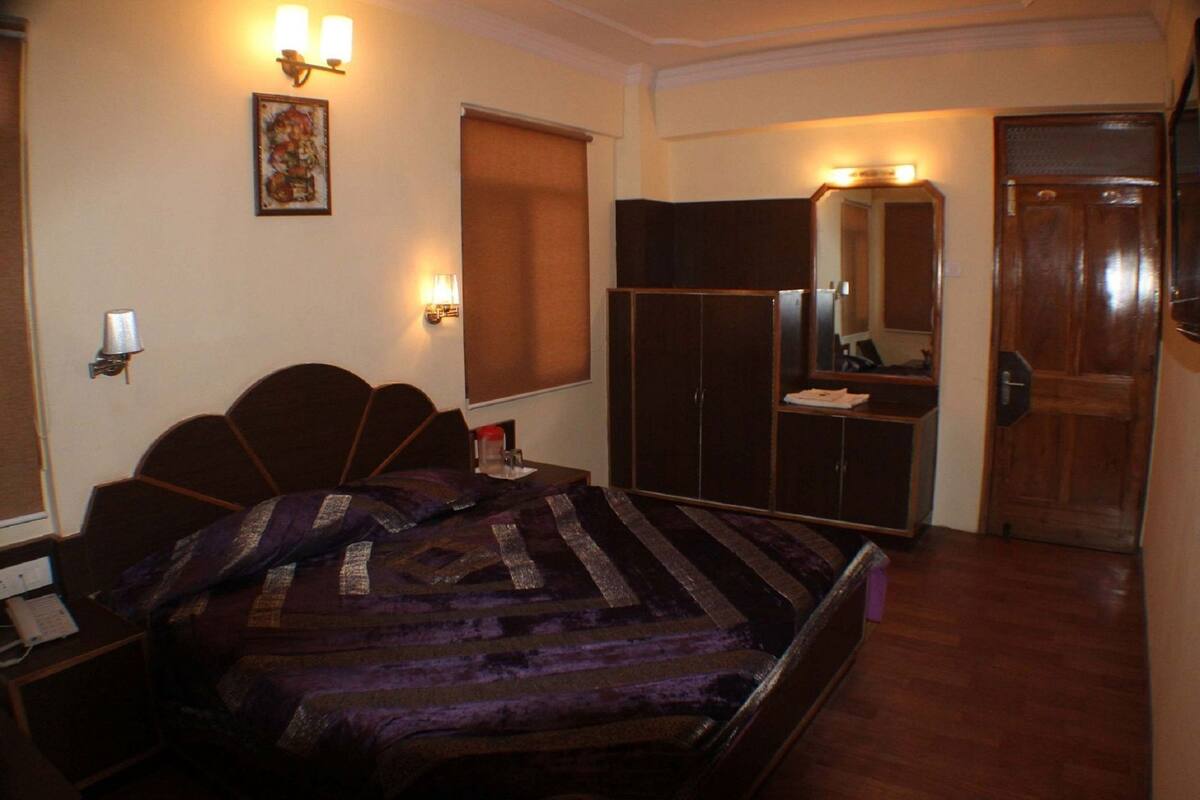 A bedroom with a bed, a wardrobe, a mirror, and a nightstand.