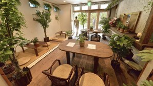 Ein Zimmer mit Holzmöbeln, Topfpflanzen und einem großen Fenster.