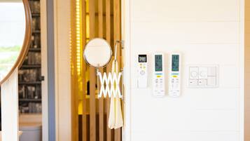 A bathroom with a mirror, towel rack, and two control panels on the wall.