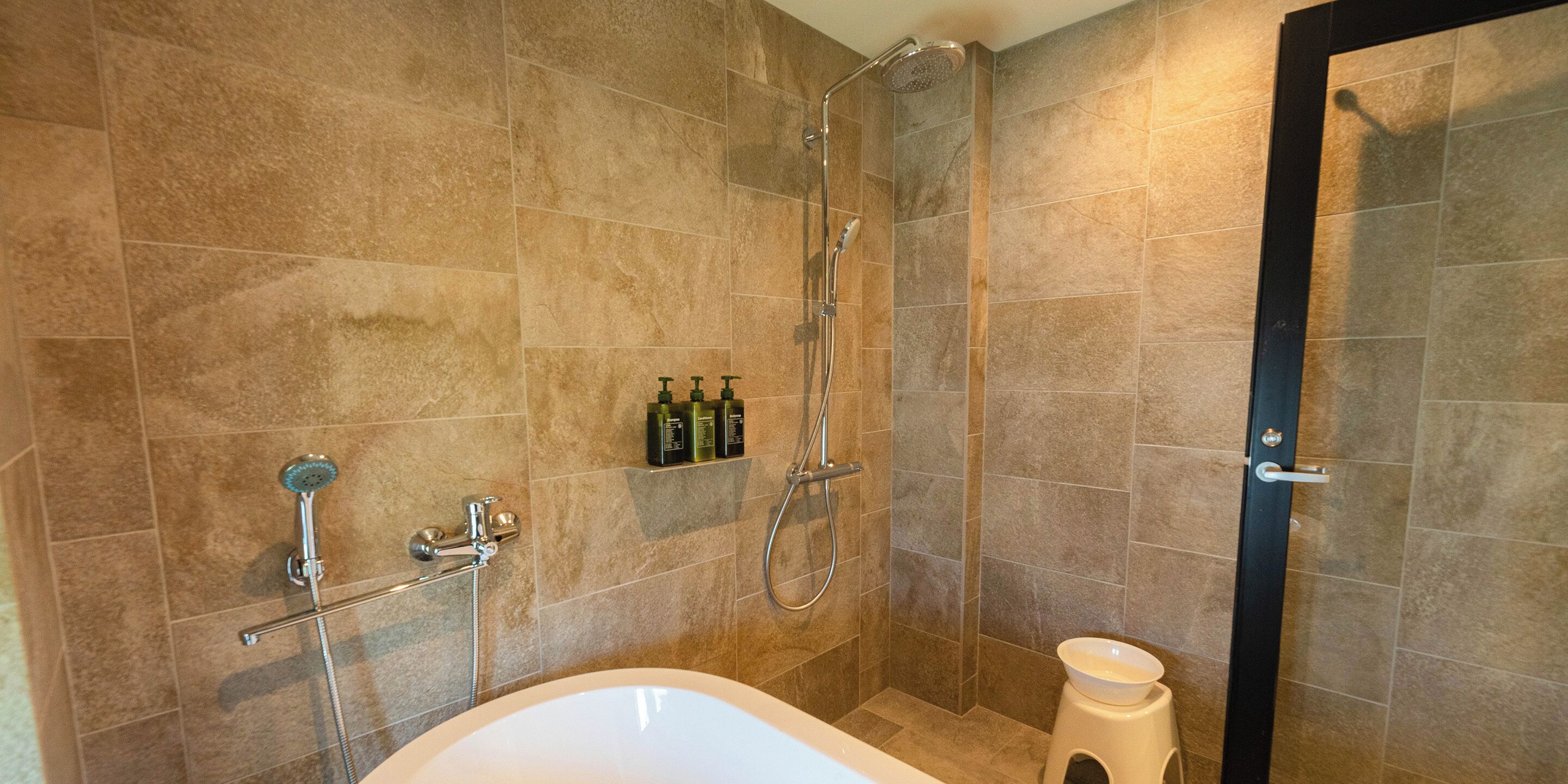 A modern bathroom with a bathtub, a shower, and a toilet.