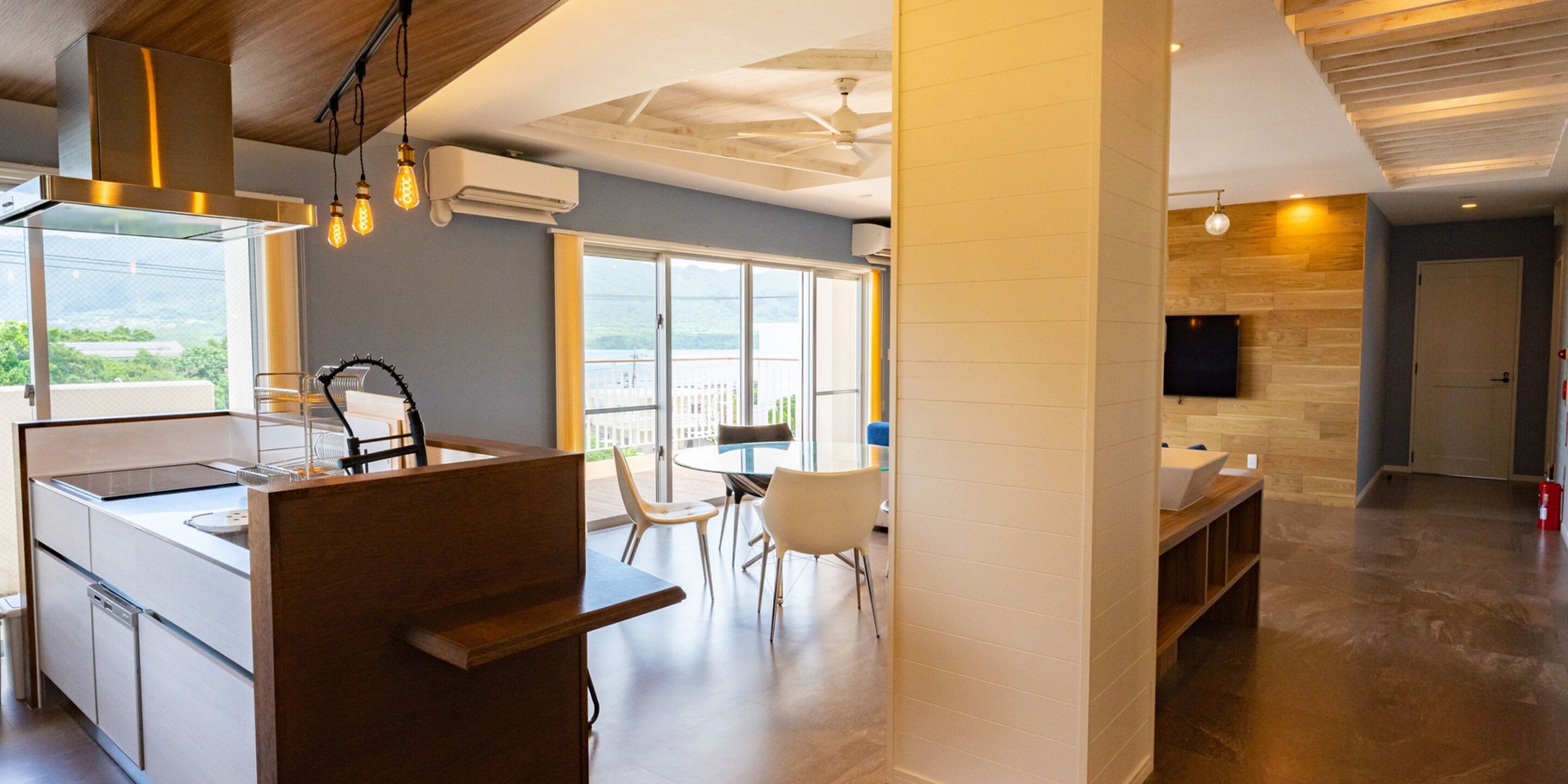 Una cocina moderna con una isla central, un comedor con sillas y un amplio ventanal con vistas.
