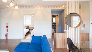Ein modernes Wohnzimmer mit einem blauen Sofa, einem Glastisch und einer Wand im Holzdesign.
