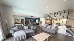 Una sala de estar moderna con un sofá seccional gris, una mesa de centro de madera y un ventanal con vistas al exterior.